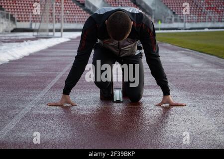 Ein sportlicher Mann auf einer Laufstrecke, der sich darauf vorbereitet Starten Sie Stockfoto
