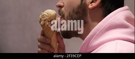 Unerkennbarer Mann leckt Eis-Kegel. Panorama-Foto-Banner. Stockfoto