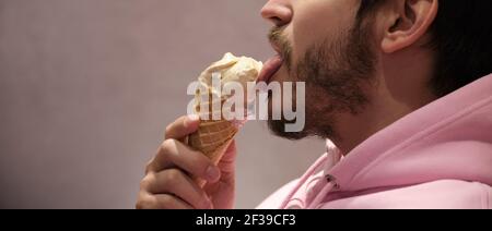 Unerkennbarer Mann leckt Eis-Kegel. Panorama-Foto-Banner. Stockfoto