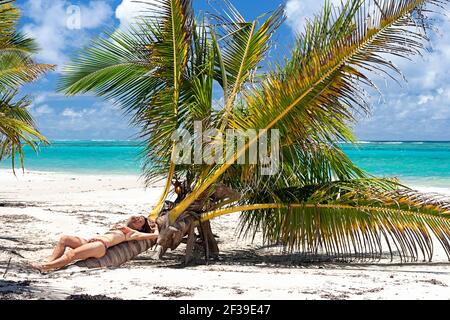 Frau liegt auf einer Palme an einem wunderschönen tropischen Strand mit weißem Sand und türkisfarbenem Meer im Norden der Ile Sainte Marie, Madagaskar Stockfoto