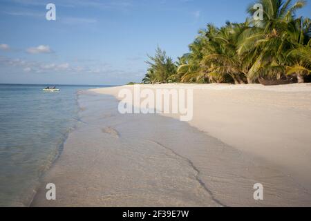 Zwei Touristen im Kanu auf der tropischen Paradiesinsel Ile aux Nattes mit weißem Sand, blauem Himmel, Palmen, smaragdfarbenem Meer. Madagaskar Stockfoto