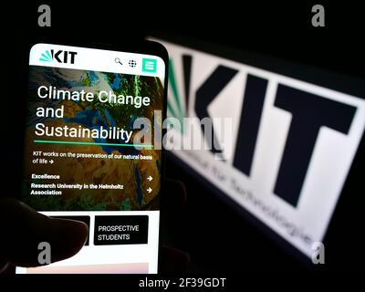Person, die Smartphone mit Webpage des Karlsruher Instituts für Technologie auf dem Bildschirm vor dem Logo hält. Konzentrieren Sie sich auf die Mitte des Telefondisplays. Stockfoto
