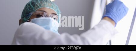 Arzt in Brille und medizinische Maske und Handschuhe hält ein Röntgenbild. Stockfoto