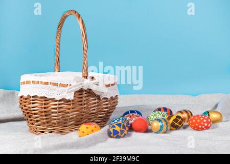 Zarte minimalistische Ostern Foto - ein Korbkorb und bemalt Eier auf blauem Hintergrund kopieren den Raum mit einem Für Text platzieren Stockfoto