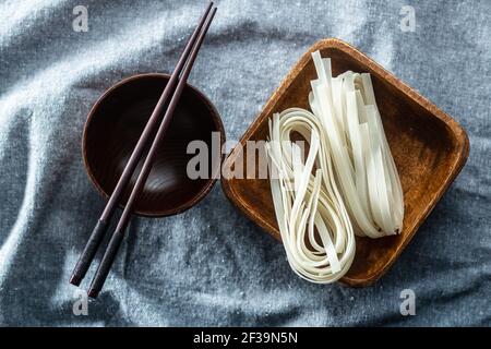 Getrocknete weiße Reisnudeln. Rohe Pasta. Ungekochte Nudeln in Holzschüssel. Draufsicht. Stockfoto