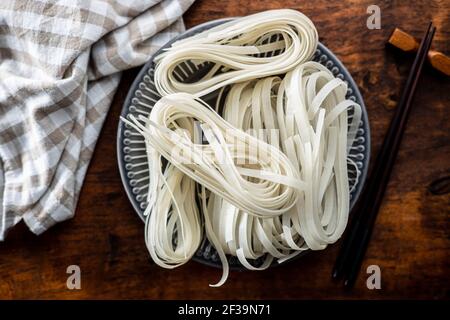 Getrocknete weiße Reisnudeln. Rohe Pasta. Ungekochte Nudeln auf dem Teller. Draufsicht. Stockfoto