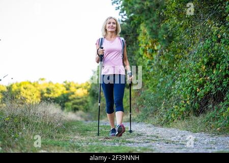 Aus der Perspektive der lächelnden, reifen Frau, die im Wald wandert Stockfoto