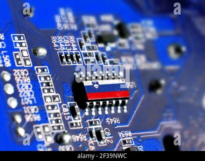 Elektronikkarte mit integriertem Mikrochip und gezeigter Flagge Sloweniens. Das Konzept moderner Computertechnologien. Stockfoto