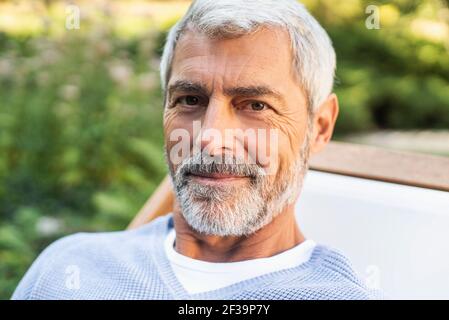 Porträt eines lächelnden reifen Mannes, der im Hinterhof sitzt Stockfoto