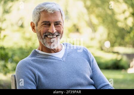 Porträt eines lächelnden, reifen Mannes, der auf einem Stuhl sitzt Stockfoto