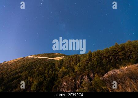Low-Angle-Ansicht des Sternenhimmels über dem baumbedeckten Berg, Canyon Matka, Skopje, Nord-Mazedonien Stockfoto