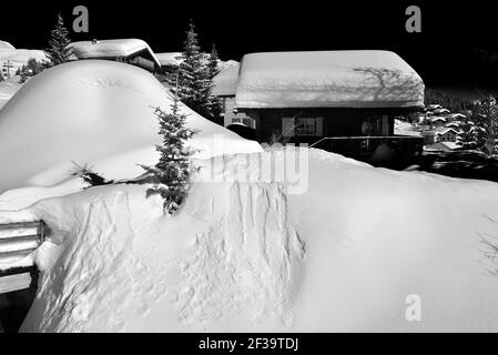 Monochrom von Chalets unter tiefem Schnee mit blauem Himmel in Ein Skigebiet Stockfoto