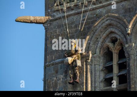 Außenansicht der Kirche von Sainte-Mere-Eglise mit ihrem Kirchturm und dem Dummy Fallschirmjäger, ein Denkmal für den amerikanischen Fallschirmjäger John Steele, der Stockfoto