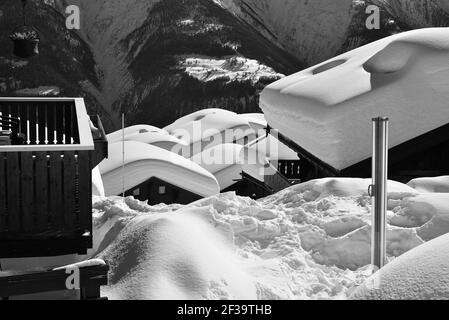 Monochrom von Chalets mit Blick unter tiefem Schnee mit Blauer Himmel in einem Skigebiet Stockfoto