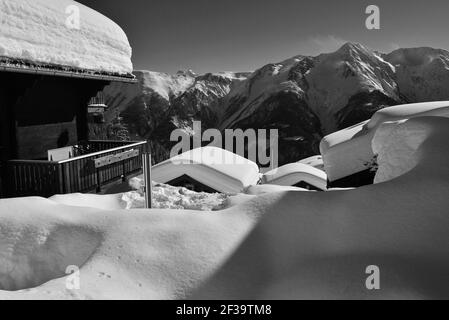 Monochrom von Chalets mit Blick unter tiefem Schnee mit Blauer Himmel in einem Skigebiet Stockfoto