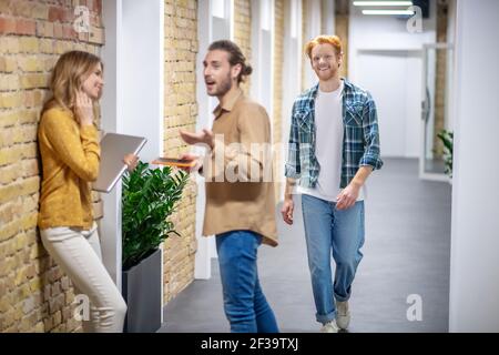 Sprechen. Junge Kollegen sprechen im Flur des Business Centers Stockfoto