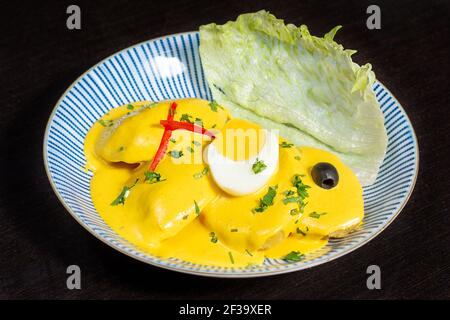 Peruanische traditionelle Küche. Kartoffeln mit Aji, gelbe Sauce, gekochte Eier, verziert mit Oliven und Pfeffer. Papa a la huancaina Stockfoto