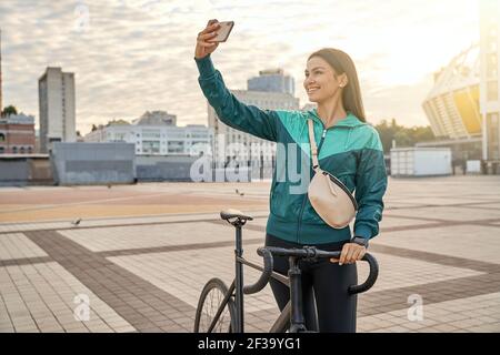Glücklich Brünette weiblich in Sportswear Foto auf dem Handy Stockfoto