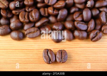Nahaufnahme von Arabica VS Robusta geröstete Kaffeebohnen mit verschwommener Kaffeebohnen stapeln sich im Hintergrund Stockfoto