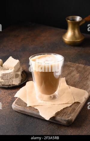 Leckerer Kaffee und Schlagschaum mit Halva auf dunkelbraunem Hintergrund. Vertikal. Nahaufnahme. Stockfoto