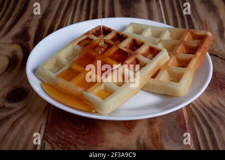 Honig auf belgischen oder Wiener Waffeln auf weißem Teller Stockfoto