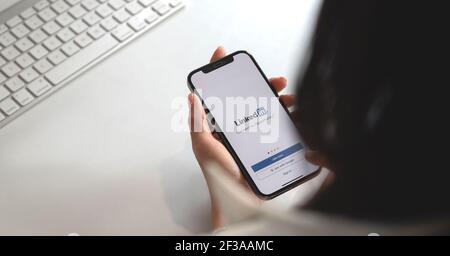 CHIANG MAI, THAILAND MAR 13, 2019 : EINE Frau hält ein iPhone 12 mit Social-Network-Service LinkedIn auf dem Bildschirm. IPhone 12 wurde erstellt und Stockfoto