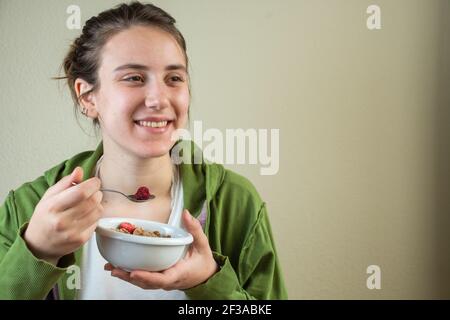 Junge Frau lächelnd, mit einer Schüssel Müsli in der Hand, Sportswear, horizontal, mit Kopierraum Stockfoto