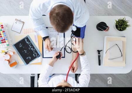 Arzt, der den Druck auf die Schulter des Patienten misst, Ansicht von oben Stockfoto