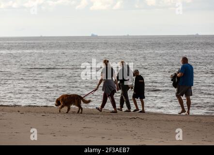 Stegna, Polen - 4. September 2020: Die Familie läuft mit ihrem Hund am Strand entlang Stockfoto