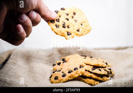 Hand nehmen Sie eine Schokolade Chip Cookie Bäckerei Käsekuchen Backen süß Lebensmittel Snack Objekt Stillleben Stockfoto