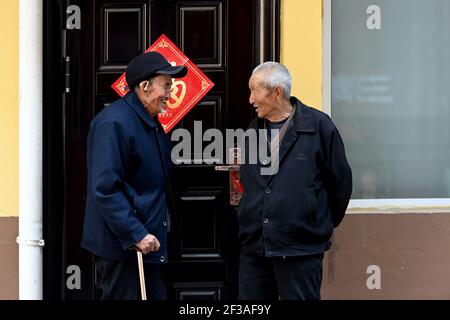 (210316) -- TAIYUAN, 16. März 2021 (Xinhua) -- Liu Qingji (L) chattet mit einem anderen Dorfbewohner in einem Wohngebiet für umgesiedelte Dorfbewohner in Yukou, Bezirk Fangshan, nordchinesische Provinz Shanxi, 9. März 2021. Shijiamao ist ein kleines Dorf in rauen Berggebieten mit wenig Niederschlag. Wie andere Dorfbewohner hier, Liu Qingji, ein 85-jähriger Landwirt, pflegte die Landwirtschaft auf Gnade der Elemente zu betreiben. Nachdem er viele Jahre in einem düsteren 'Yaodong', einem Haus, das in die verhärtete Erde gebaut wurde, die auf dem Löss-Plateau in Nordchina verbreitet ist, lebte, hoffte Liu, die Lebensbedingungen zu verbessern Stockfoto