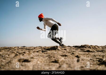 Athletic african american Sportler in Kopfhörer laufen während des Trainens Am Strand Stockfoto