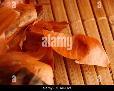 Die Verwendung von Zwiebelschalen in der Medizin und zum Färben von Ostereiern. Zwiebelhaut und Zwiebel auf Holzgrund. Stockfoto