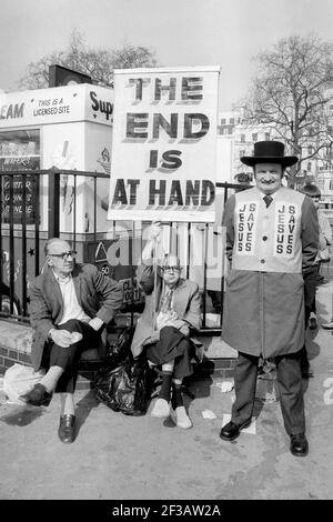 Drei ältere Männer in der Nähe von Speakers Corner im Hyde Park London England Großbritannien das Ende trägt Banner und Jesus rettet Jacke fotografiert im Jahr 1984. Stockfoto