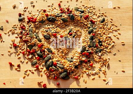 Food Hintergrund der Mischung aus Gewürzen, Gewürzen und Samen schließen mit selektivem Fokus in Form von Herz auf Holzbrett, goldenen Leinsamen, Kürbis siehe Stockfoto