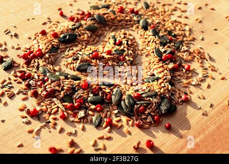 Food Hintergrund der Mischung aus Gewürzen, Gewürzen und Samen schließen mit selektivem Fokus in Form von Herz auf Holzbrett, goldenen Leinsamen, Kürbis siehe Stockfoto