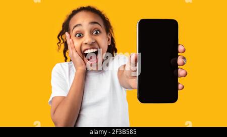 Aufgeregt schwarze Mädchen zeigt leere Smartphone-Bildschirm für mockup Stockfoto