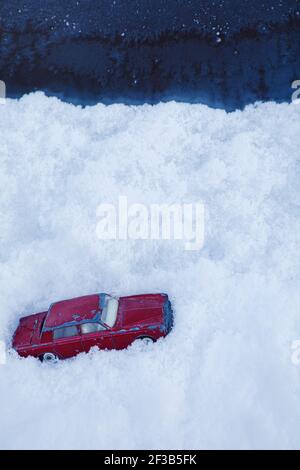 Rotes Spielzeug Auto in tiefen Schnee Drift Schneesturm stecken. Konzept der gefangen, Klimawandel, extreme Wetter Stockfoto