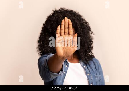 afroamerikanische Frau versteckt sich hinter ihrer Handfläche Stockfoto