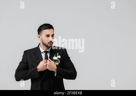 Arabischer Bräutigam schaut weg, während das Tragen Jacke isoliert auf grau Stockfoto