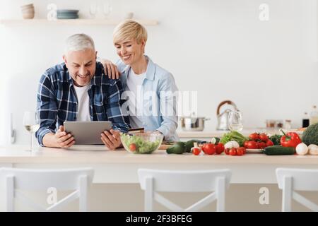 Glückliches Seniorenpaar verwenden Tablette, Kreditkarte, Bestellung der Lieferung von Lebensmitteln im Lebensmittelgeschäft auf dem Markt tun Einkaufen Stockfoto