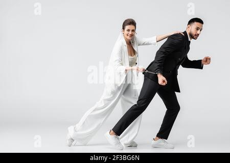 Lächelnde Braut stoppen laufen muslim Bräutigam in Handschellen auf weiß Hintergrund Stockfoto