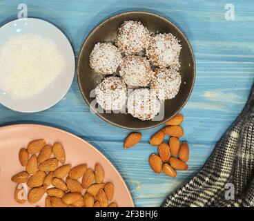 Marzipan Süßigkeiten mit geriebener Kokosnuss auf Holzhintergrund bedeckt. Runde weiße Süßigkeiten mit Kokosflocken. Hausgemachte Snacks. Gesunde Ernährung für Stockfoto