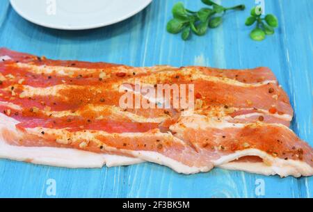 Roher Speck auf einem Holzhintergrund. Frisches Schweinefleisch mit Kräutern und Gewürzen Stockfoto