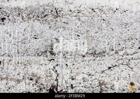 Eine alte Betonwand mit Rissen, die mit weißer Farbe bedeckt sind. Grunge Hintergrund. Hochwertige Fotos Stockfoto