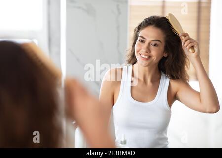 Fröhlich Weiblich Kämmen Und Bürsten Sie Wellig Haar Im Badezimmer Stockfoto