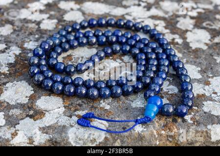 Blaue mala Perlen (Lapislazuli) auf Stein, aus der Nähe und Blick von oben. Buddhistische Gebetsperlen für die Japa-Meditation Stockfoto