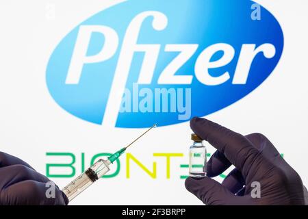 CLUJ-NAPOCA -RUMÄNIEN - MÄRZ 9 2021: Pfizer-Impfstoff Covid-19 Konzept. Spritzennadel und Impfstoff, verschwommenes Firmenlogo von Pfizer auf dem Hintergrund. Stockfoto