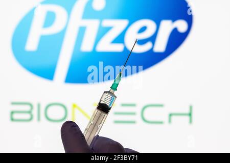CLUJ-NAPOCA -RUMÄNIEN - MÄRZ 9 2021: Pfizer-Impfstoff Covid-19 Konzept. Spritzennadel und Impfstoff, verschwommenes Firmenlogo von Pfizer auf dem Hintergrund. Stockfoto