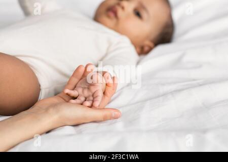 Niedliche kleine afroamerikanische Baby im Bett mit Mutter liegen Stockfoto